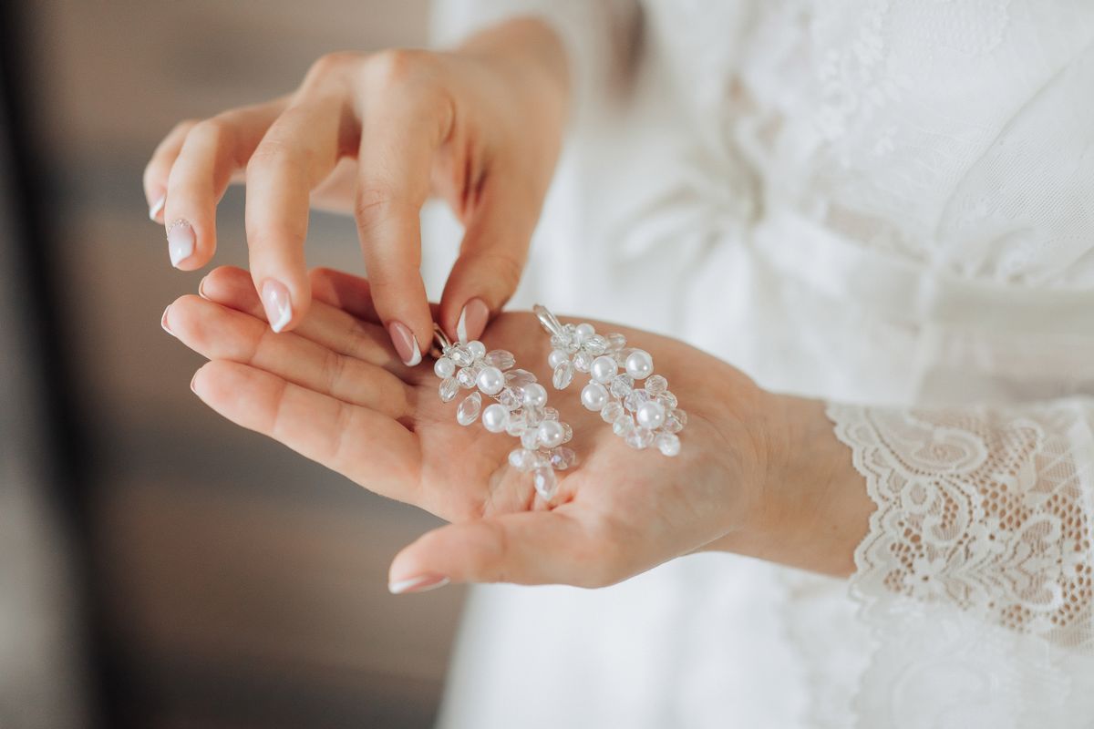 Bride's hands holding crystal earrings while getting ready